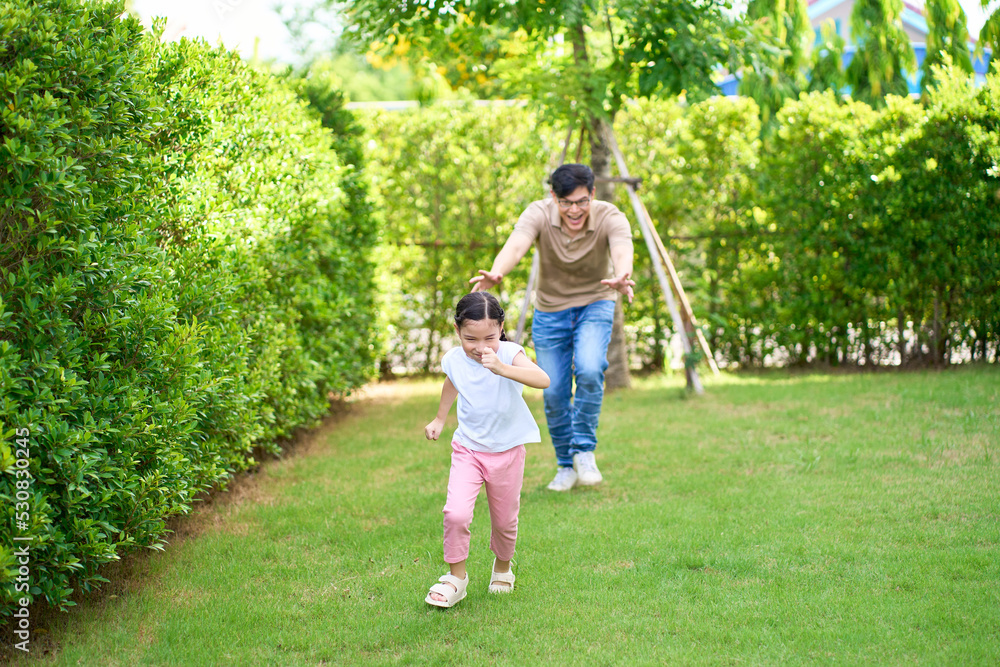 Girl running with her dad on home garden , Family playing time concept