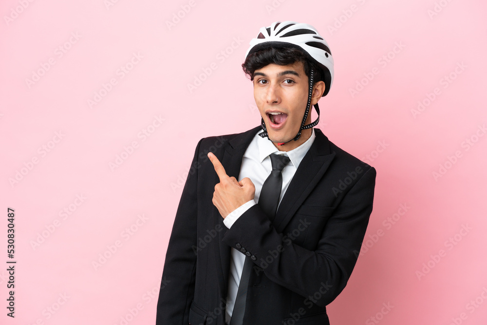 Argentinian businessman with bike helmen isoleted on pink background Argentinian businessman with bike helmen isoleted on pink background