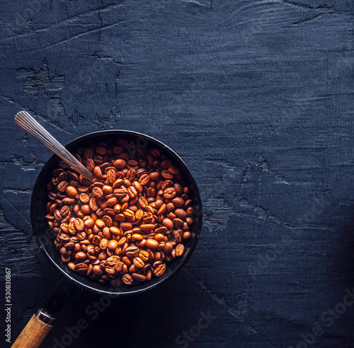 Brown light roasted coffee beans in pan on wooden background