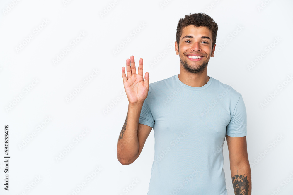Young handsome Brazilian man isolated on white background saluting with hand with happy expression Young handsome Brazilian man isolated on white background saluting with hand with happy expression