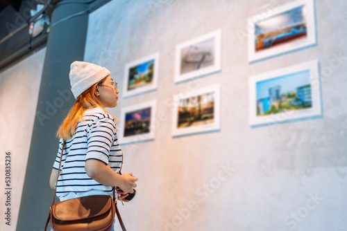 Woman visiting art gallery her looking pictures on wall watching photo frame painting at artwork museum people lifestyle concept. photo