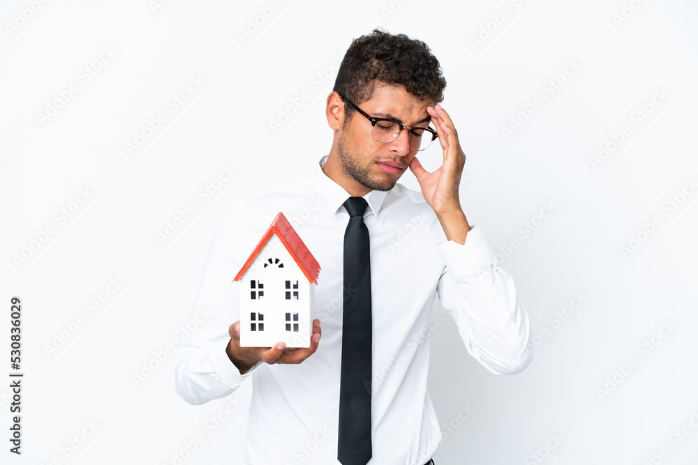 Young business Brazilian man holding a house toy isolated on white background with headache