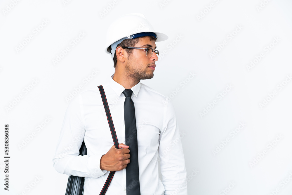 Architect brazilian man with helmet and holding blueprints looking to the side Architect brazilian man with helmet and holding blueprints looking to the side
