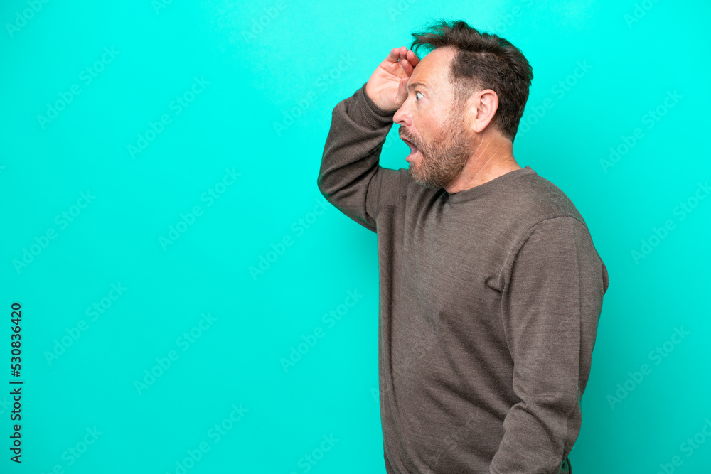 Middle age caucasian man isolated on blue background with surprise expression while looking side Middle age caucasian man isolated on blue background with surprise expression while looking side