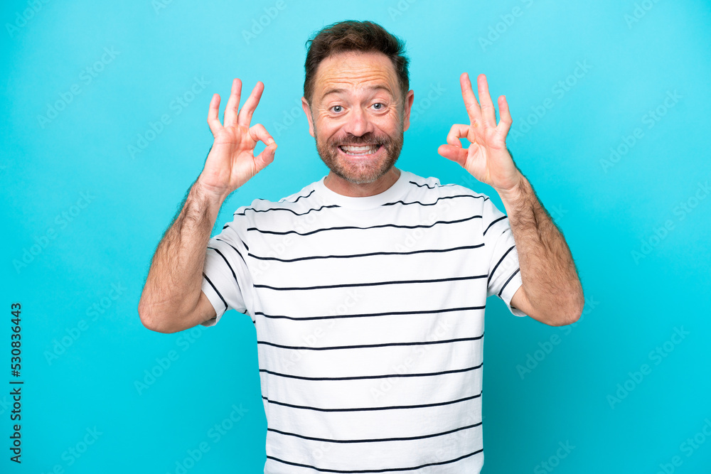 Middle age caucasian man isolated on blue background showing ok sign with two hands Middle age caucasian man isolated on blue background showing ok sign with two hands