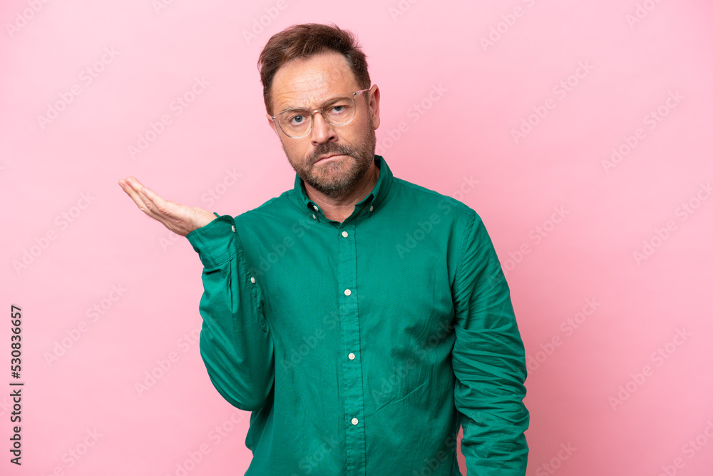 Middle age caucasian man isolated on pink background having doubts Middle age caucasian man isolated on pink background having doubts