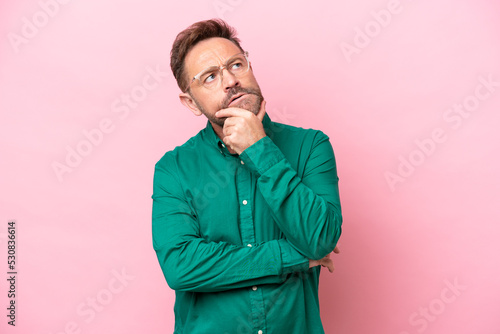 Middle age caucasian man isolated on pink background having doubts © luismolinero