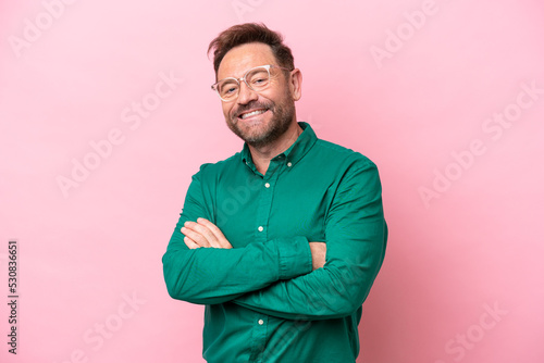 Middle age caucasian man isolated on pink background with arms crossed and looking forward
