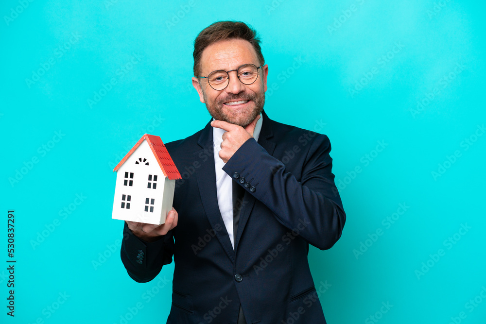 Real estate middle age agent man isolated on blue background happy and smiling Real estate middle age agent man isolated on blue background happy and smiling