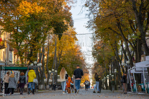 People walk along the romantic autumn streets of the city. Pedestrian urban area.