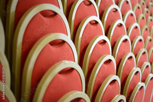 rows of red and gold cinema and theater chairs for spectators and audiences
