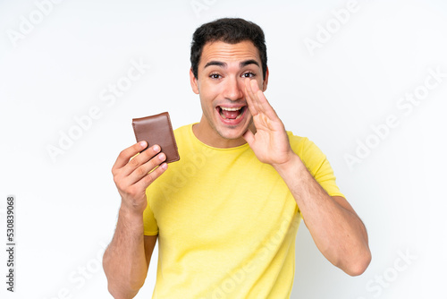 Young caucasian man holding a wallet isolated on white background shouting with mouth wide open