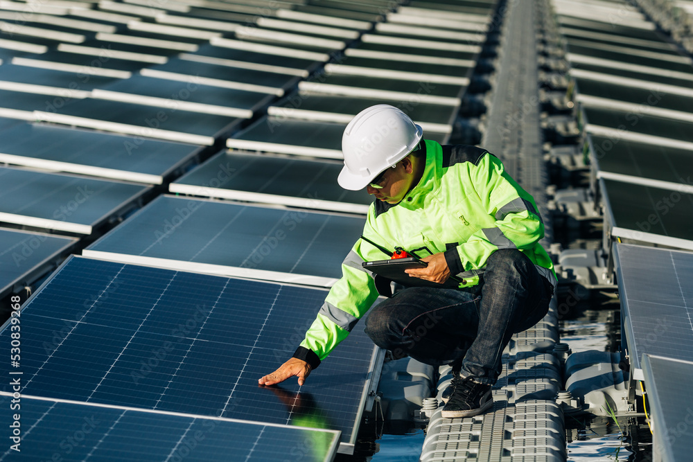 The portrait of a asian young engineer checks photovoltaic solar panels. Concept. renewable energy technology electricity service, green power. The portrait of a asian young engineer checks photovoltaic solar panels. Concept. renewable energy technology electricity service, green power.