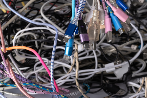 Pile of tangled old smart technology wires, used charging cables and connectors for electronic devices. The concept of recycling and disposal of electronic waste.