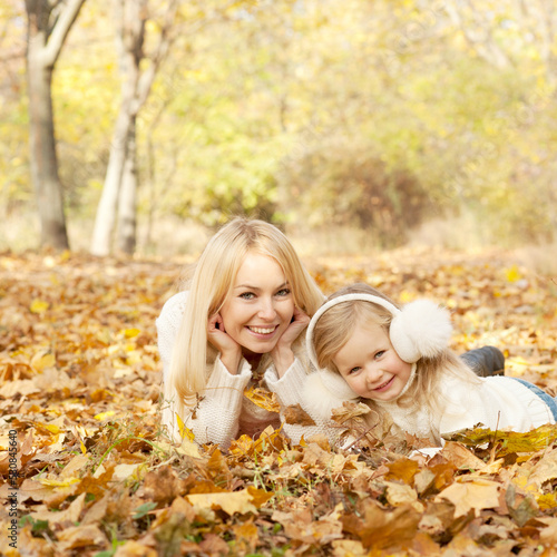 Happy joyful family portrait, mother and daughter have a rest laying outdoor in autumn park