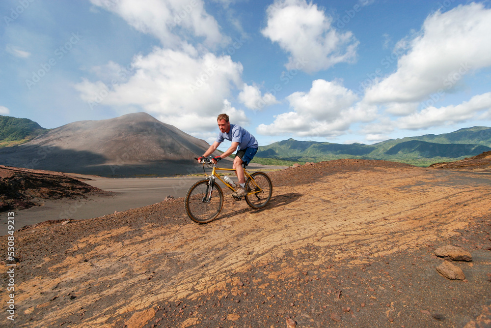 Western tourist riding a mountain bike on Yasur Volcano, Tanna Island, Vanuatu
