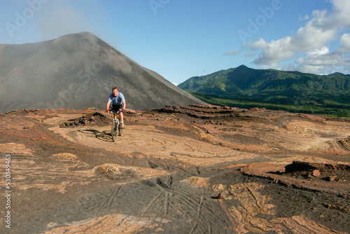 Western tourist riding a mountain bike on Yasur Volcano, Tanna Island, Vanuatu