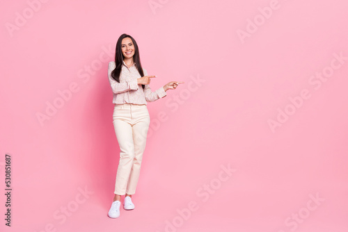 Full length photo of positive lady promoter point finger empty space presenting adverts isolated pastel color background