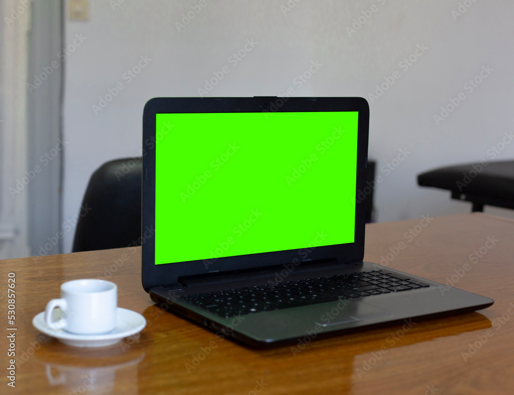 Close up view of an office laptop and coffee with mock up green screen browsing internet at work desk. Close up view of an office laptop and coffee with mock up green screen browsing internet at work desk.