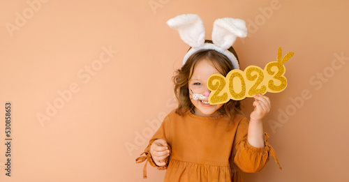 A funny laughing child in the guise of a rabbit closes his eye with the numbers 2023. The year according to the zodiac sign of the Eastern calendar. Christmas Greeting poster