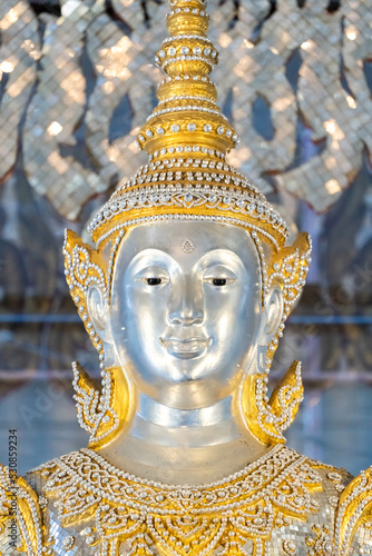 Deity statue standing straight made of silver, wearing silver gold costume with Chada on top of his head. Surrounded by sparkleling decoration. photo