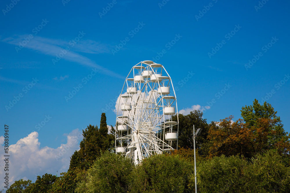 Ferris wheel in Bardolino, sunshine and blue sky, tourist attraction Ferris wheel in Bardolino, sunshine and blue sky, tourist attraction