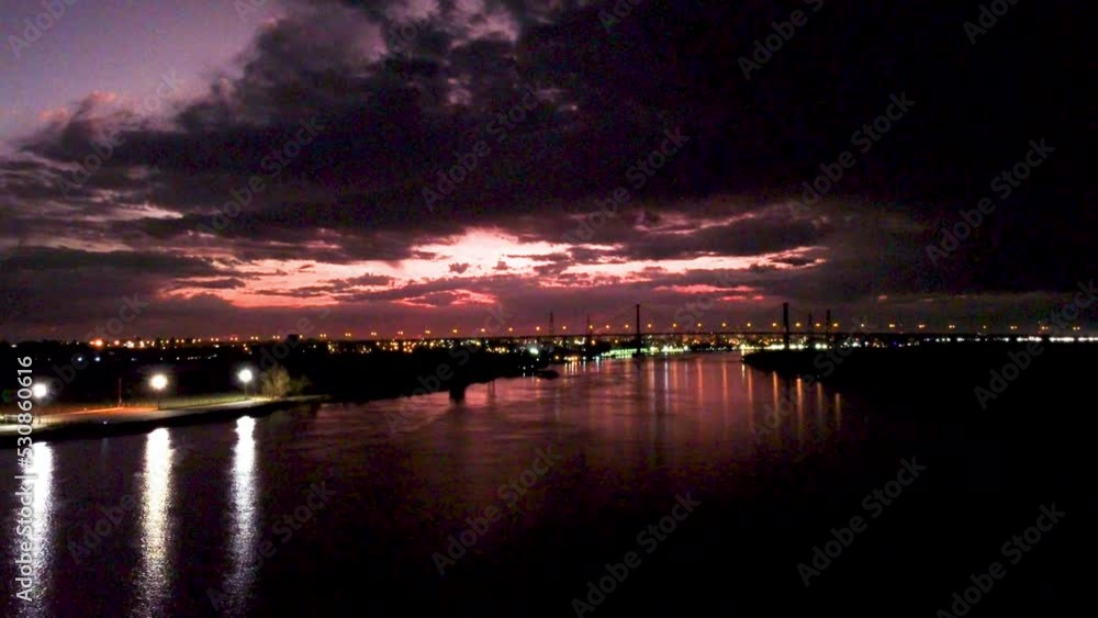 Night time lights reflecting on a river purple ominous skies with city lights in the background aerial video Night time lights reflecting on a river purple ominous skies with city lights in the background aerial video