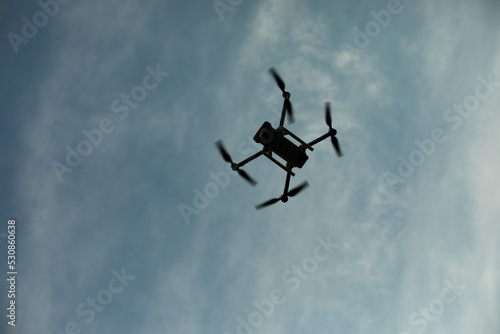 Drone in sky. Quadro copter flies in air. Surveillance from height. Four propellers.