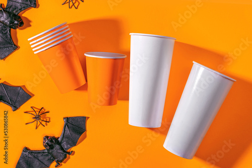 Halloween party background with Paper cup with spiders, bats. Disposable cup made of recycled paper orange colors. Pattern for outumn october holiday all saints day celebration photo