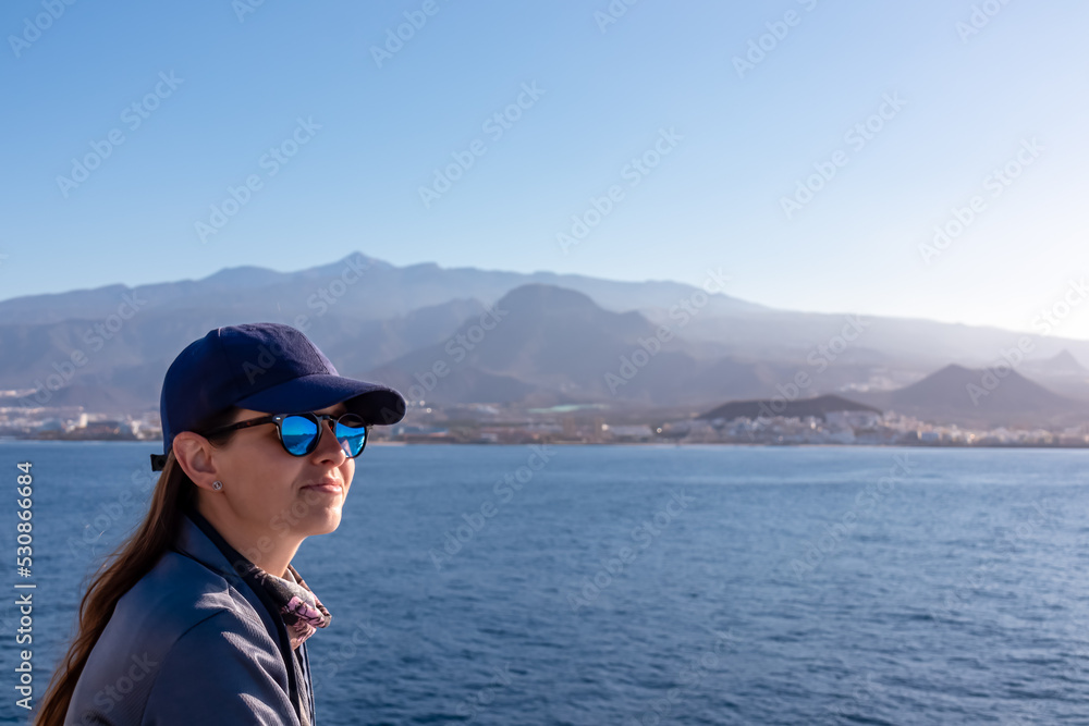 Woman enjoying the panoramic view from a ferry on the landscape around volcano mount Pico del Teide, Canary Islands, Spain, Europe. Boat is connecting Tenerife and La Gomera. Island hopping vacation