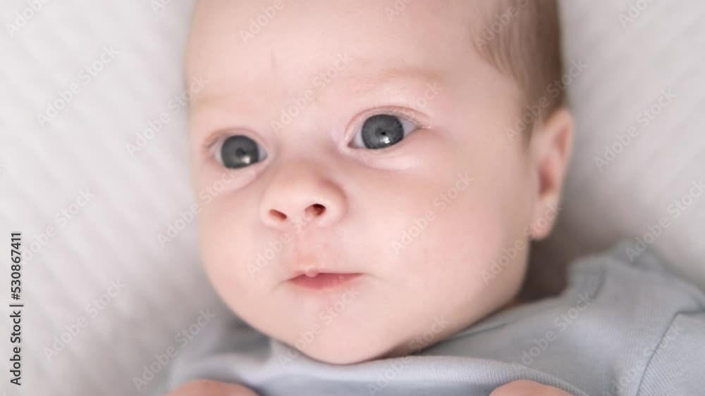 Portrait newborn baby boy lying in nursery cocoon with blue clothes on bed in bedroom at home, happy baby morning Portrait newborn baby boy lying in nursery cocoon with blue clothes on bed in bedroom at home, happy baby morning