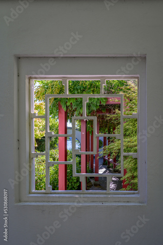 Verwunschener Ort: Blick durch ein steinernes Ornamentfenster in den Chinesischen Garten von Zeuthen photo