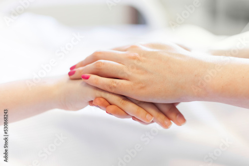nurse per patient holding patient's hand and supporting her