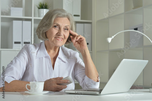 Elderly woman in headphones take online course on computer at home.
