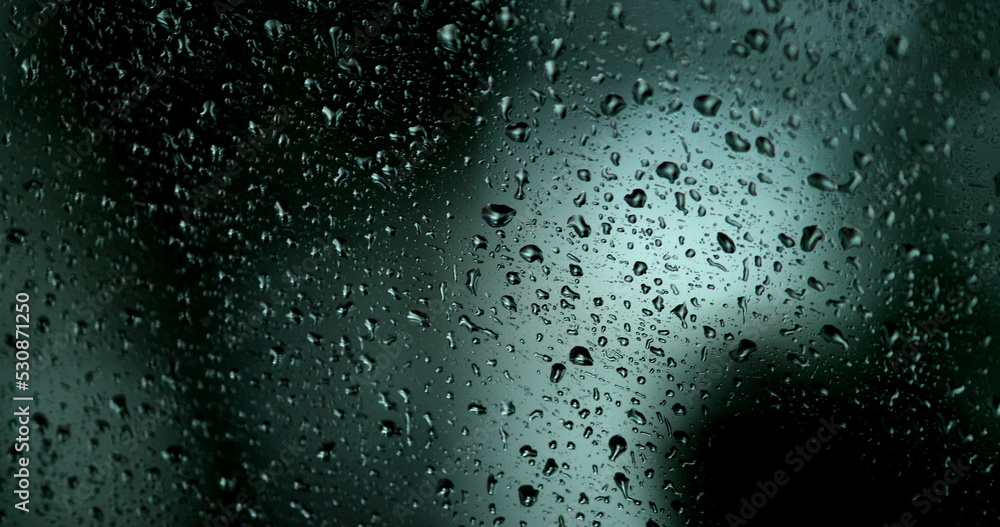 Droplets on car window with background in motion. Driving during rainy day