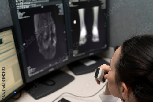 Valokuvatapetti radiology doctor examines foot, ankle x-ray, mr image and reports with microphone looking computer screen, X-ray analysis room reading X-rays of a heel, toe and other parts of the body