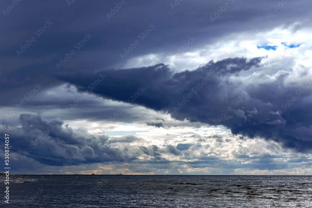 Fototapeta premium Funnel - shaped horizontal clouds on stormy dark cloudy sky over Baltic sea just before a sea storm in Riga, Latvia. Nature environment concept. Weather Forecast Concept.