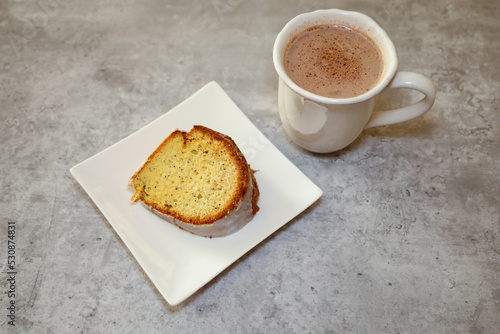 A piece of poppy seed bread and a cup of hot cocoa.