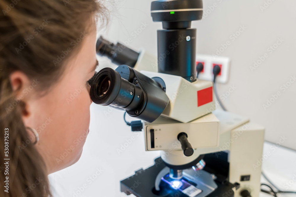 scientist looking through a microscope in a laboratory doing research, microbiological analysis, medicine. Scientist looking in microscope in laboratory