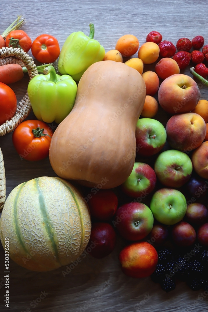 Round straw bag and various healthy fruits and vegetables on wooden background.