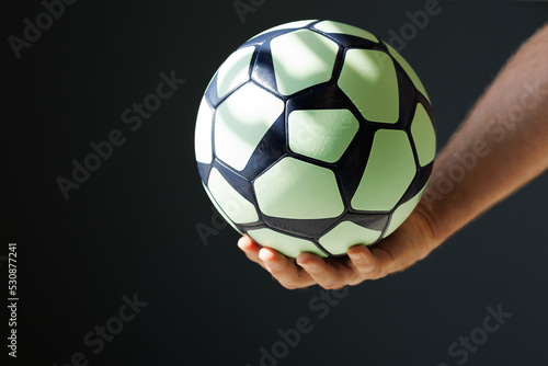 green black ball for handball in the athlete's hand on a black background