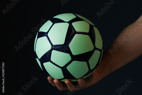 green black ball for handball in the athlete s hand on a black background