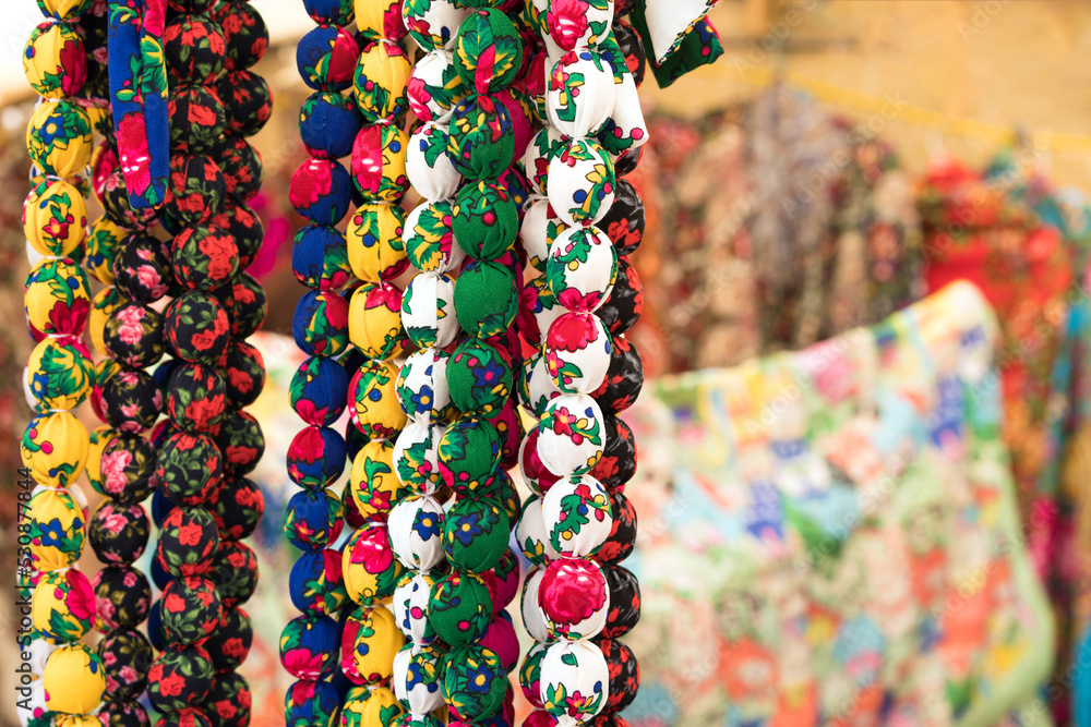 Colorful necklaces in folk or ethnic chic style as background with copy space. Handmade fabric necklaces at souvenir stall or street market
