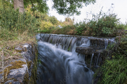 a small waterfall from a mountain river flows through the forest, close-up. A beautiful landscape of wild nature