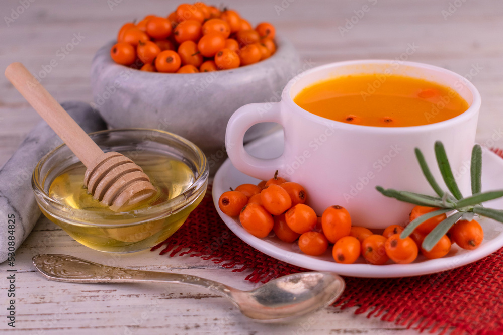 Healthy sea buckthorn and honey tea on a white wooden background.
Healthy sea buckthorn and honey tea on a white wooden background.
