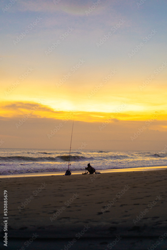 A fisherman is fishing with a fishing rod on the ocean, Bali, Indonesia.