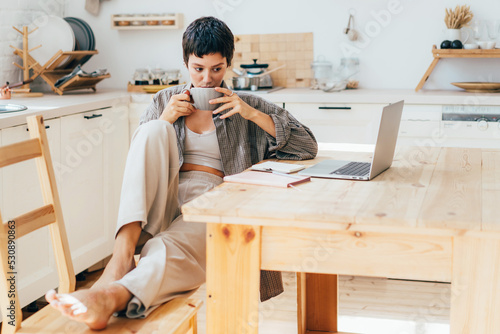 Young woman drinking coffee has a break while working on computer gadgets. photo