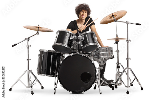 Smiling young male drummer holding drumsticks and sitting with a drum set