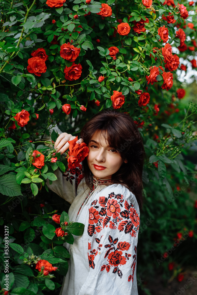 a girl in a national dress on a background of green plants a girl in a national dress on a background of green plants