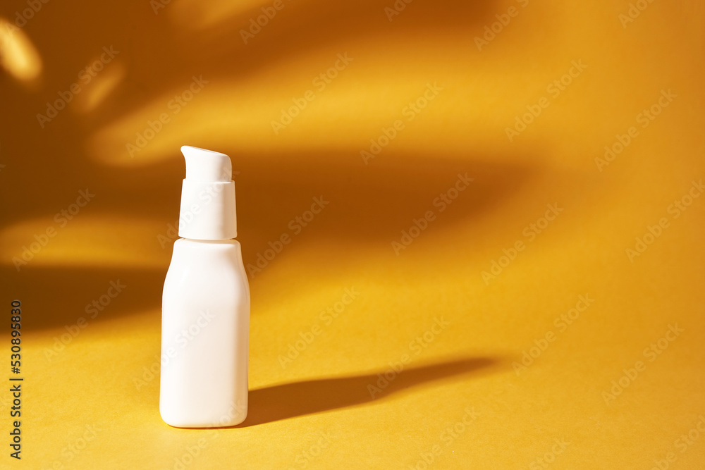 Cosmetic white bottle with a dispenser on a yellow background. The shadow of the monstera plant on the surface. Skin care. A container for cosmetic products for skin care. High quality photo Cosmetic white bottle with a dispenser on a yellow background. The shadow of the monstera plant on the surface. Skin care. A container for cosmetic products for skin care. High quality photo